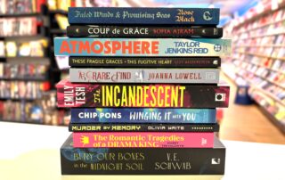 A stack of books on the Information Desk in ABC The Hague, with the store in the background.
